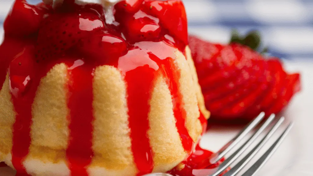 A luscious close-up of a glass jar filled with rich, vibrant strawberry syrup. The syrup glistens invitingly, its deep red hue evoking the sweetness of fresh, ripe strawberries. Soft, natural lighting illuminates the jar, casting gentle shadows that accentuate the syrup's thick, velvety texture. The jar is positioned on a wooden surface, with a few fresh strawberries scattered around, hinting at the ingredients and the homemade nature of the recipe. The overall scene conveys a sense of warmth, indulgence, and the comforting flavors of a classic strawberry shortcake dessert. The Ultimate Strawberry Shortcake Syrup Recipe