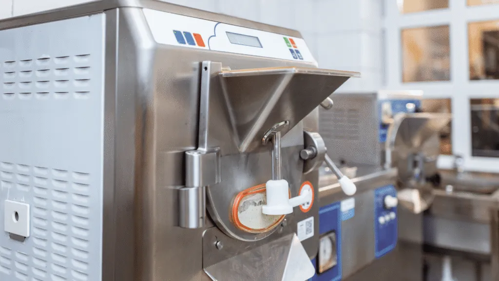 A sleek, compact ice cream maker set against a minimalist, well-lit background. The device has a smooth, modern design with clean lines and a glossy white exterior. It is positioned prominently in the foreground, capturing the viewer's attention. The middle ground features a simple, neutral-toned backdrop, allowing the ice cream maker to be the focal point. The lighting is soft and diffused, creating a warm, inviting atmosphere. The overall scene conveys a sense of simplicity, functionality, and ease of use, reflecting the "easy" nature of the device. The image would effectively illustrate the "Design, Cleaning, and Storage Insights" section of the article. Dash Mini Ice Cream Maker Design, Cleaning, and Storage Insights