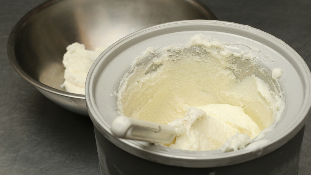 A sleek, stainless steel bowl filled with a creamy, smooth vanilla ice cream base, glistening under warm, golden lighting. The surface is unmarked, save for a subtle sheen, hinting at the rich, velvety texture within. Surrounding the bowl, a minimalist, modern kitchen counter, with clean lines and a subtle gray tone, creating a simple, elegant backdrop. The overall scene exudes a sense of culinary refinement, perfectly capturing the essence of a homemade, artisanal ice cream recipe, ready to be transformed into a delightful treat using a high-performance Ninja ice cream maker.