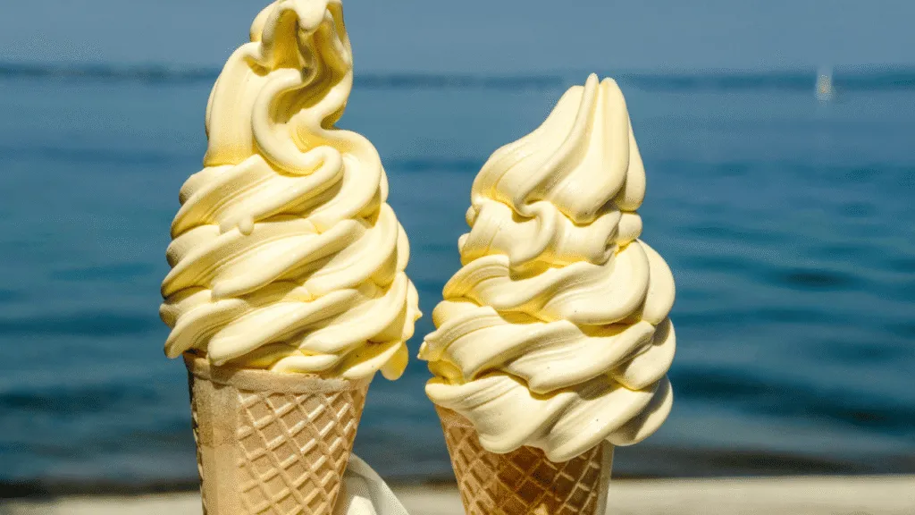 A crisp, clean kitchen countertop with a gleaming ice cream maker. In the foreground, a chef's hands skillfully manipulate the ice cream, swirling and folding the creamy, glistening butterscotch-colored mixture. Soft, warm lighting casts a cozy glow, highlighting the intricate textures and fluid motions. In the background, a chalkboard menu displays the tempting "Butterscotch Ice Cream" offering, with vintage-inspired illustrations. The overall scene exudes a sense of artisanal craftsmanship, inviting the viewer to imagine the rich, indulgent flavor of the freshly churned ice cream. Master the butterscotch ice cream recipe
