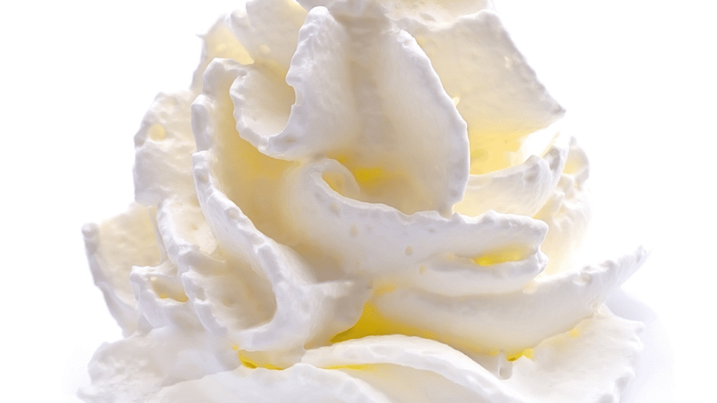 A crisp, well-lit close-up shot of fresh pineapple and coconut chunks arranged on a dark wooden surface. The pineapple slices are golden and juicy, their jagged crown leaves adding a tropical touch. Grated coconut shavings are scattered artfully around the pineapple, their white hues contrasting beautifully. The lighting is soft and diffused, casting gentle shadows that accentuate the texture and shape of the ingredients. The overall composition is balanced and visually appealing, drawing the viewer's attention to the key components of this delicious dessert. Dole Whip Ninja Creami Key Ingredients and Their Roles
