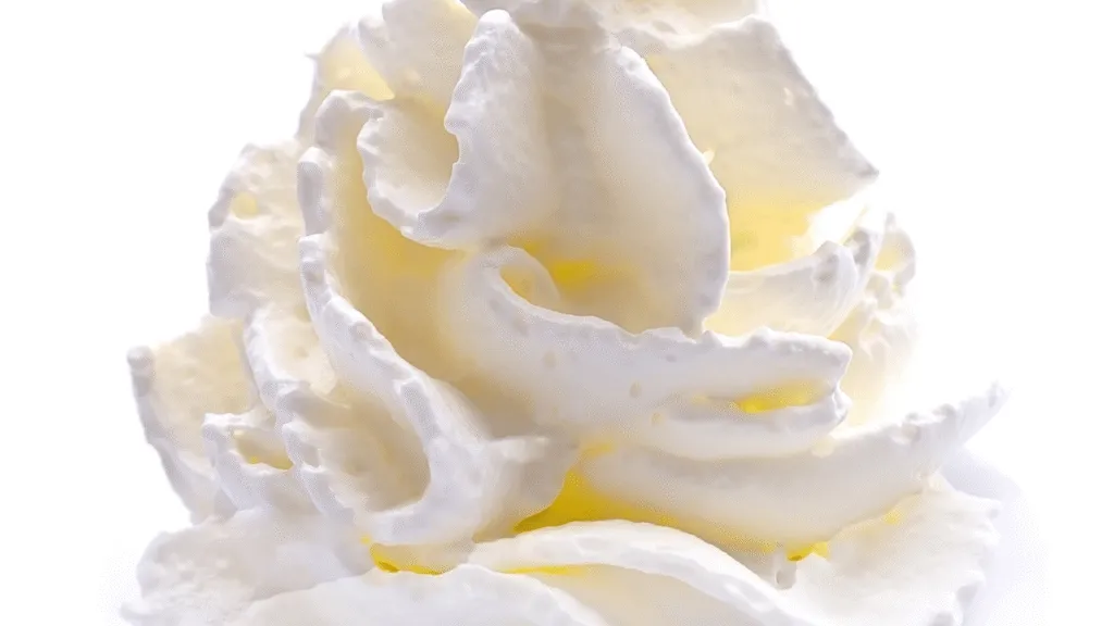 A crisp, well-lit close-up shot of fresh pineapple and coconut chunks arranged on a dark wooden surface. The pineapple slices are golden and juicy, their jagged crown leaves adding a tropical touch. Grated coconut shavings are scattered artfully around the pineapple, their white hues contrasting beautifully. The lighting is soft and diffused, casting gentle shadows that accentuate the texture and shape of the ingredients. The overall composition is balanced and visually appealing, drawing the viewer's attention to the key components of this delicious dessert. Dole Whip Ninja Creami Key Ingredients and Their Roles