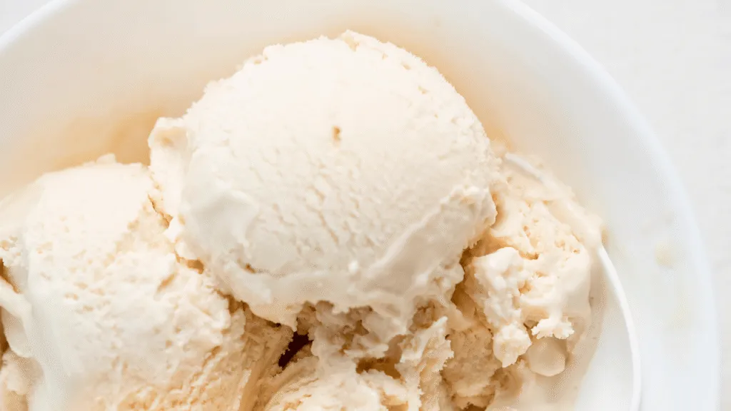 A close-up shot of a hand slowly pouring a stream of pure vanilla extract into a stainless steel mixing bowl filled with a creamy, pale yellow ice cream base. The vanilla flows gracefully, its fragrant essence enveloping the scene. Soft, diffused lighting casts a warm, homey glow, highlighting the creamy texture of the ice cream mixture. The background is blurred, drawing the viewer's focus to the simple, yet essential act of "adding vanilla" - a key step in crafting delicious homemade ice cream treats. The mood is one of calm, comfort, and the joy of creating something wholesome and delicious from scratch. A close-up shot of a hand slowly pouring a stream of pure vanilla extract into a stainless steel mixing bowl filled with a creamy, pale yellow ice cream base. The vanilla flows gracefully, its fragrant essence enveloping the scene. Soft, diffused lighting casts a warm, homey glow, highlighting the creamy texture of the ice cream mixture. The background is blurred, drawing the viewer's focus to the simple, yet essential act of "adding vanilla" - a key step in crafting delicious homemade ice cream treats. The mood is one of calm, comfort, and the joy of creating something wholesome and delicious from scratch.