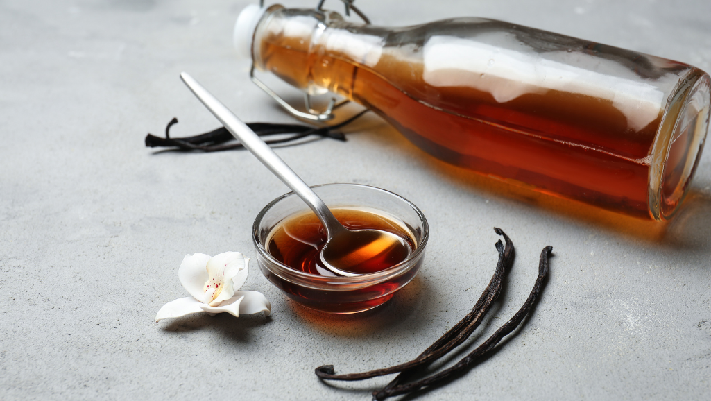 a high-resolution close-up of a single vanilla bean pod, resting on a wooden cutting board, with a soft, warm lighting that casts gentle shadows, showcasing the pod's rich, dark-brown color and the delicate vanilla bean seeds visible within, the image conveying a sense of simplicity, elegance, and the foundational essence of classic vanilla flavor