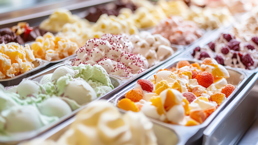 A juicy, vibrant scoop of fruit-forward ice cream, its surface glistening with tiny droplets of condensation. The bright, luscious flavors of berries, citrus, and tropical fruits swirl together in a creamy, decadent base. Warm, soft lighting casts a golden glow, casting dramatic shadows that accentuate the texture and shape of the scoop. The composition is slightly off-center, creating a sense of motion and energy. The background is blurred, placing the focus squarely on the captivating ice cream. Hints of complementary colors - a splash of purple, a touch of green - add depth and complexity to the image.