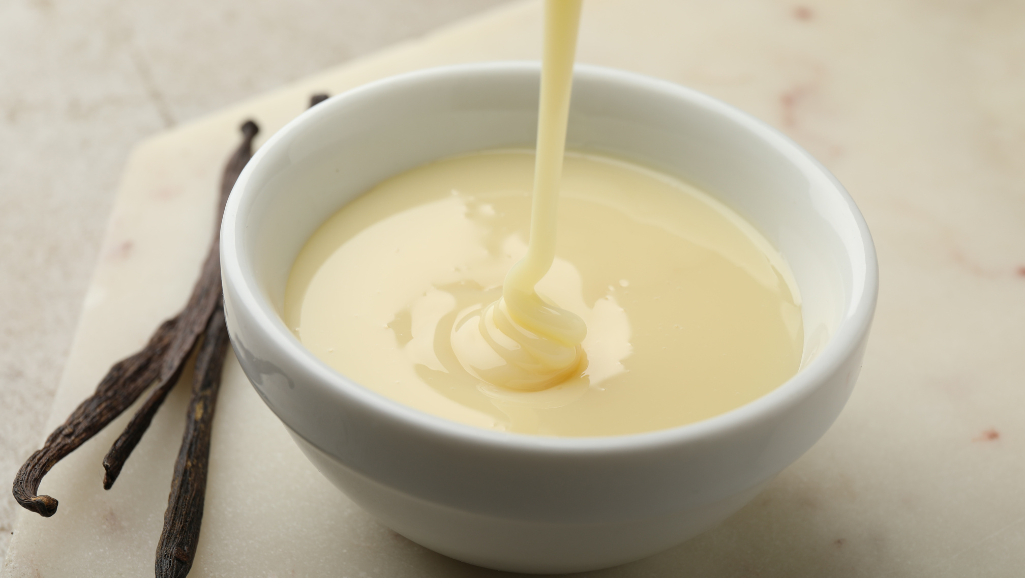 A delicate white tin can filled to the brim with thick, creamy sweetened condensed milk. The label is crisp and pristine, reflecting the warm golden tones of a soft, diffused lighting. The can is placed on a clean, white surface, casting a faint shadow that adds depth and dimension. The overall scene evokes a sense of simplicity, indulgence, and the promise of a rich, decadent treat - the perfect ingredient for a creamy, homemade ice cream.