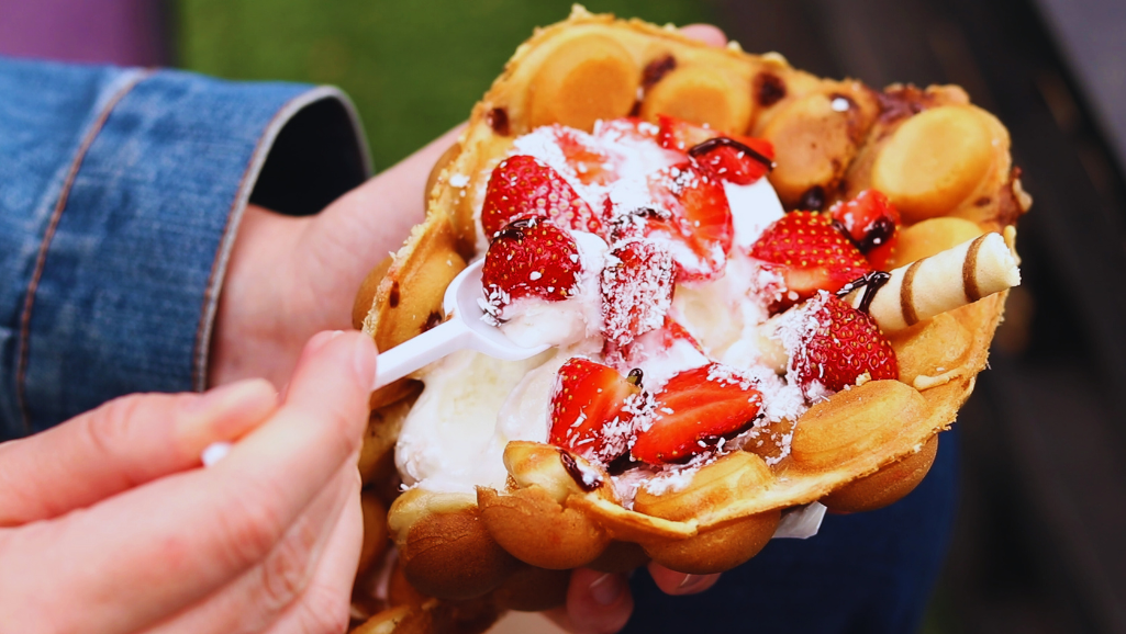 A close-up composition focusing on eggs arranged in a neat, organized manner on a rustic wooden kitchen countertop. In the foreground, two shells are cracked open, revealing bright, golden yolks and smooth whites, symbolizing cooked and uncooked eggs. In the middle ground, a softly glowing vintage thermometer indicates an ideal safe cooking temperature, surrounded by a few fresh herbs for contrast. The background features a blurred kitchen setting with a hint of ice cream-making utensils, like a churn and spatula, subtly tying into the theme. Soft, warm lighting creates an inviting atmosphere, emphasizing safety and comfort in cooking. The camera angle is slightly overhead, providing a dynamic perspective, while maintaining clarity and focus on the eggs and cooking tools.