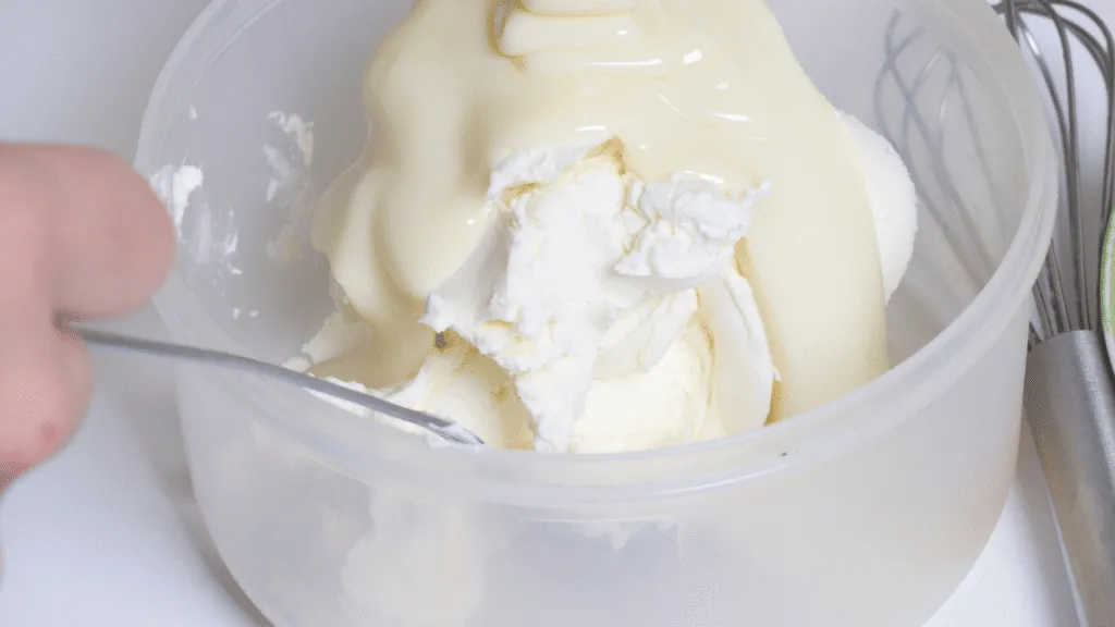 A closeup of a freshly whipped cream, glistening with a smooth, creamy texture. The cream is piled high in the center of the frame, casting soft, diffused shadows that create depth and dimensionality. Lighting is soft and natural, with a slight hazy, ethereal quality that enhances the dreamy, indulgent atmosphere. The background is minimalist and blurred, allowing the whipped cream to take center stage and command the viewer's attention. The overall composition is balanced and visually appealing, perfectly capturing the essence of a homemade, creamy ice cream ingredient. Homemade ice cream condensed milk recipe: step‑by‑step